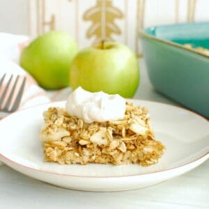 A healthy apple oatmeal bar topped with a dollop of yogurt on a white plate.