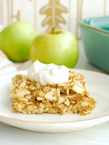 A healthy apple oatmeal bar topped with a dollop of yogurt on a white plate.