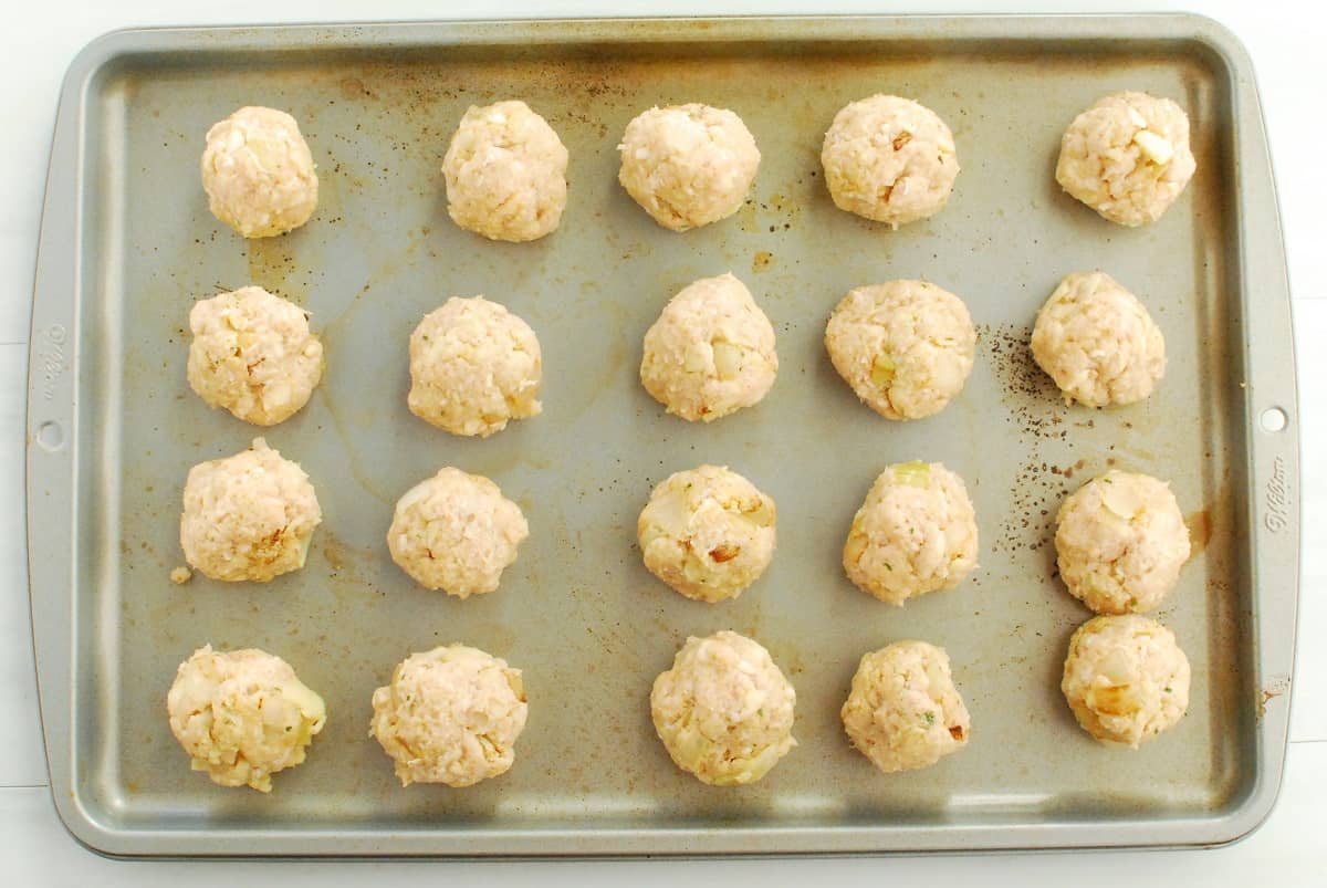 Uncooked meatball on a baking sheet.