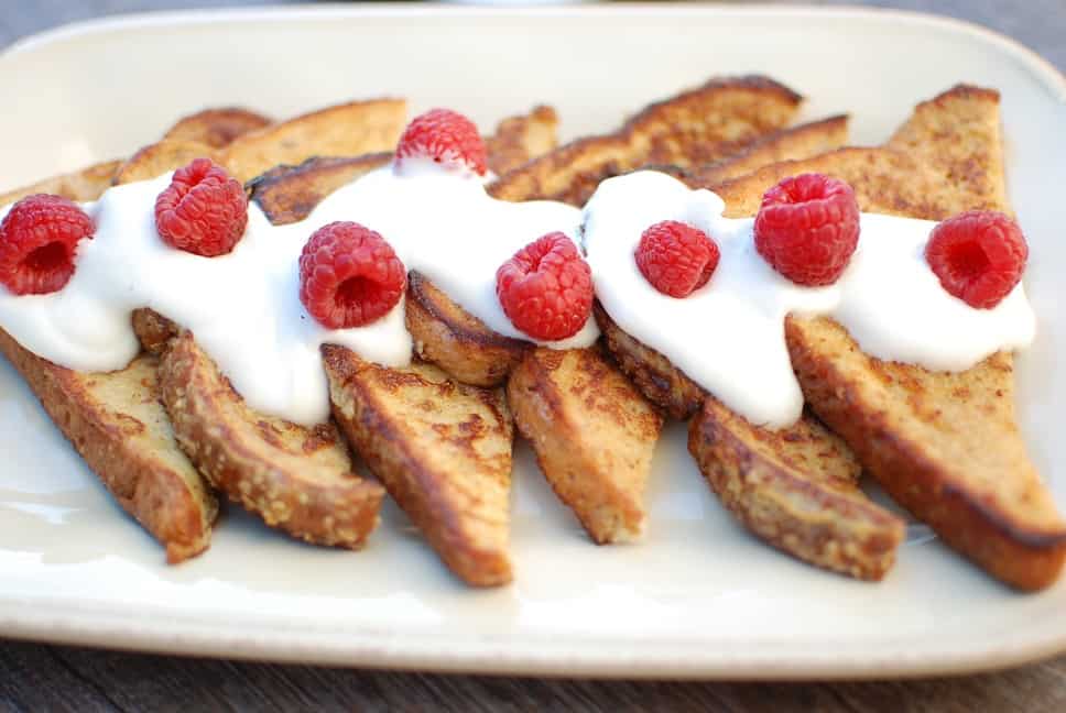 A platter of eggnog french toast topped with raspberries.