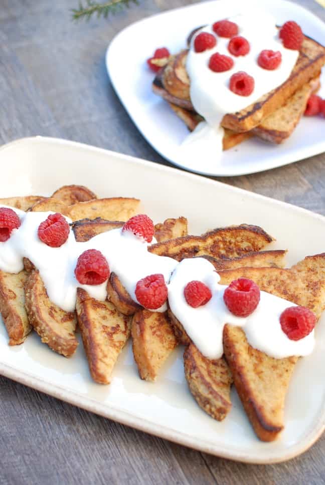 A plate with half slices of eggnog french toast with a greek yogurt and raspberry topping.