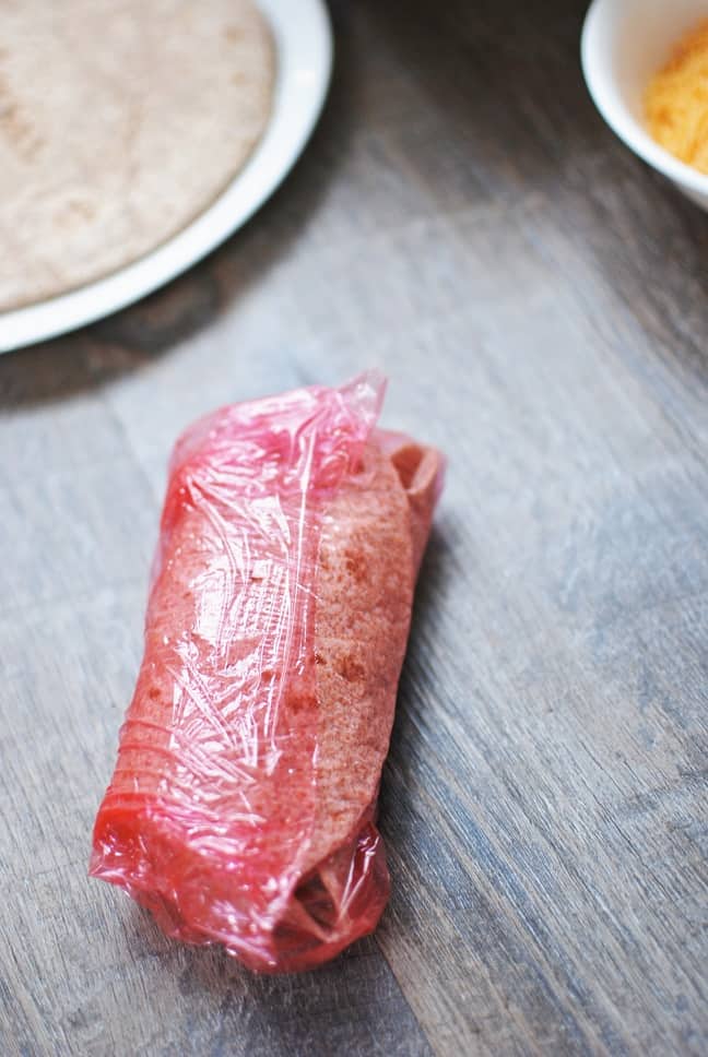 A breakfast burrito in plastic wrap.