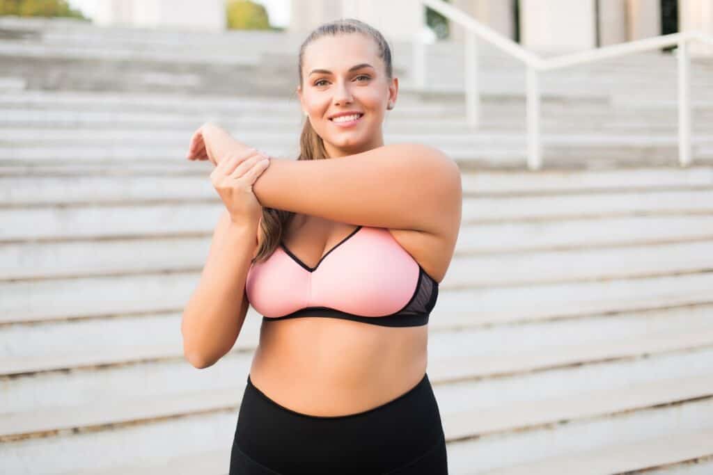 A woman stretching her arms outside.