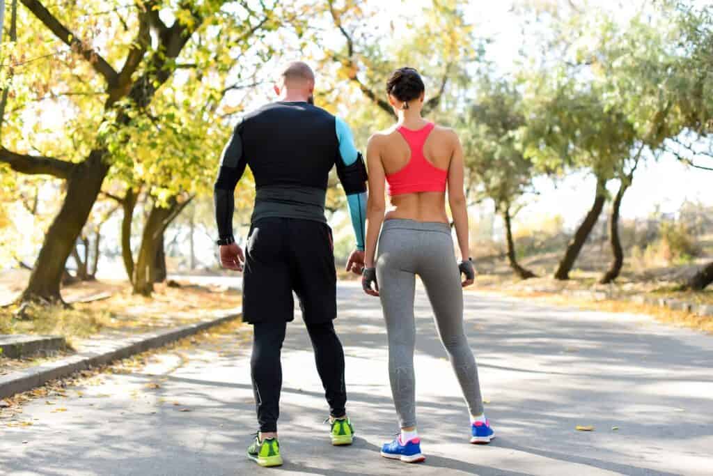 A man and a woman working out together outdoors.