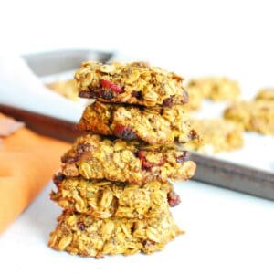 A stack of five pumpkin oatmeal breakfast cookies next to an orange napkin.