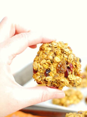 A woman's hand holding a pumpkin oatmeal breakfast cookie.