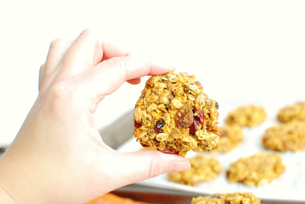 A woman's hand holding a pumpkin oatmeal breakfast cookie.