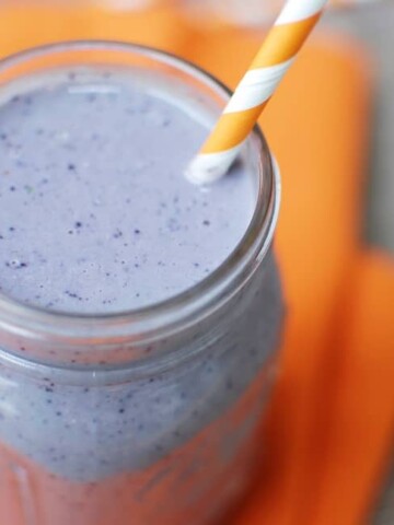 A blueberry pancake smoothie in a mason jar with a straw.