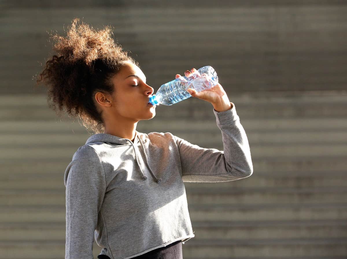 A woman drinking water after a run.