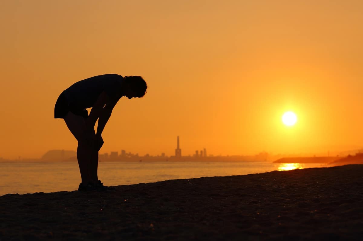 A man feeling tired after an outdoor run at sunset.