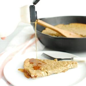A baked apple oatmeal pancake being drizzled with maple syrup.