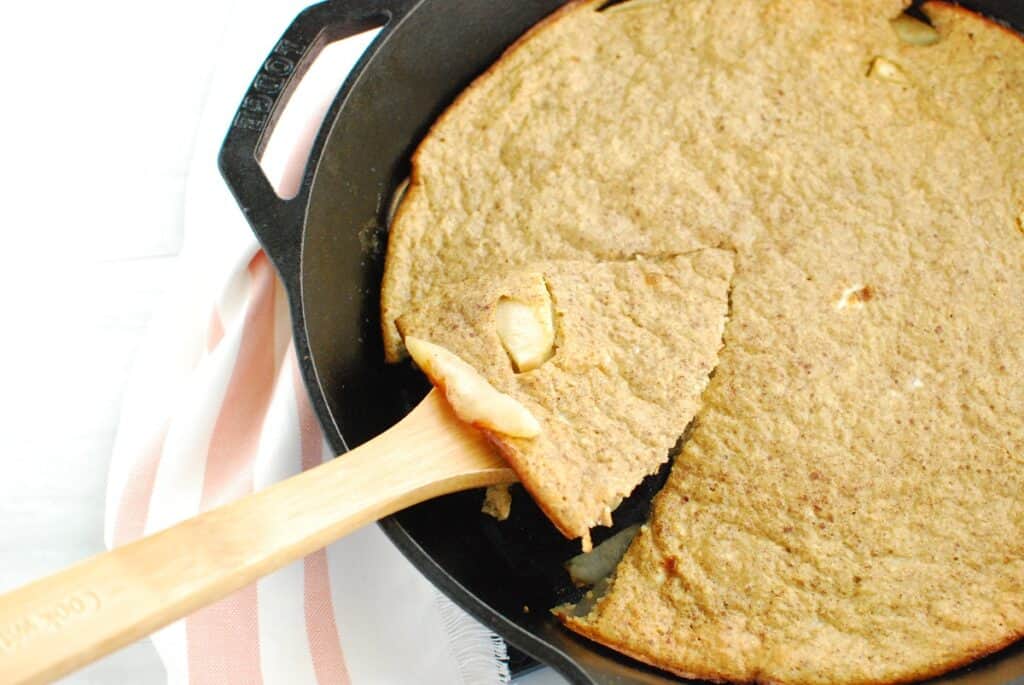 A wooden spoon scooping out a piece of the baked oatmeal pancake.