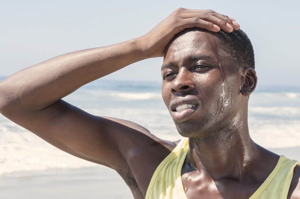 A runner sweating heavily outside on a sunny day.
