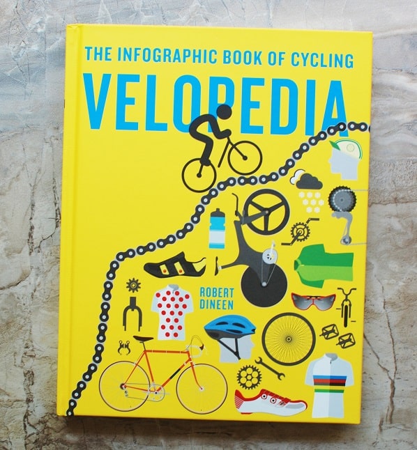 Velopedia cycling book on a grey table.