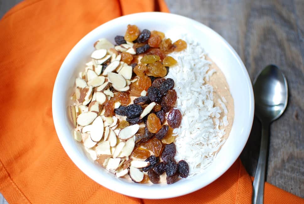 A carrot cake smoothie bowl topped with almonds, raisins, and coconut
