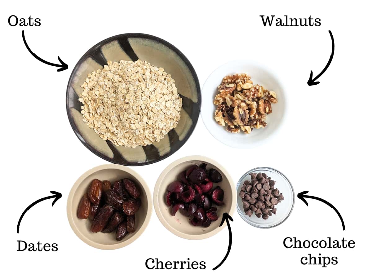 Oats, walnuts, dates, cherries, and chocolate in bowls.