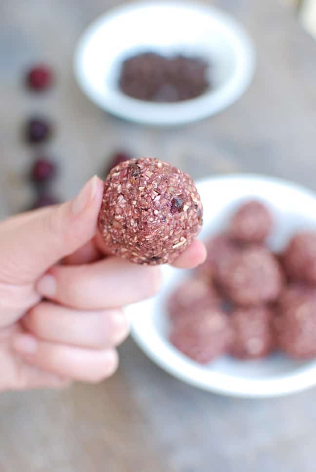 A woman's hand holding a chocolate cherry energy ball.