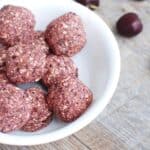 A close up of a chocolate cherry energy ball in a bowl.