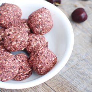 A close up of a chocolate cherry energy ball in a bowl.