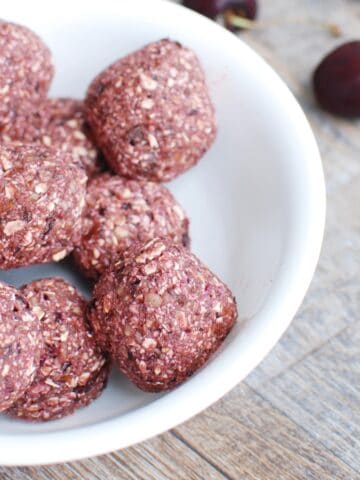 A close up of a chocolate cherry energy ball in a bowl.