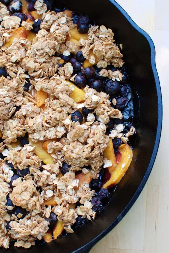 Healthy peach blueberry crisp in a cast iron skillet.