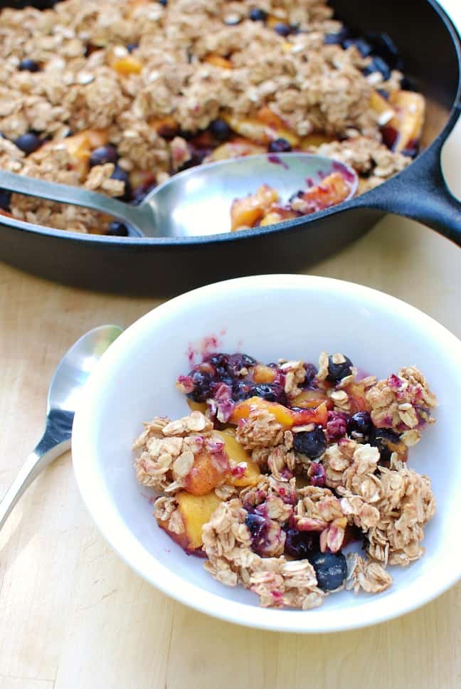 A serving of peach blueberry crisp in a white bowl.