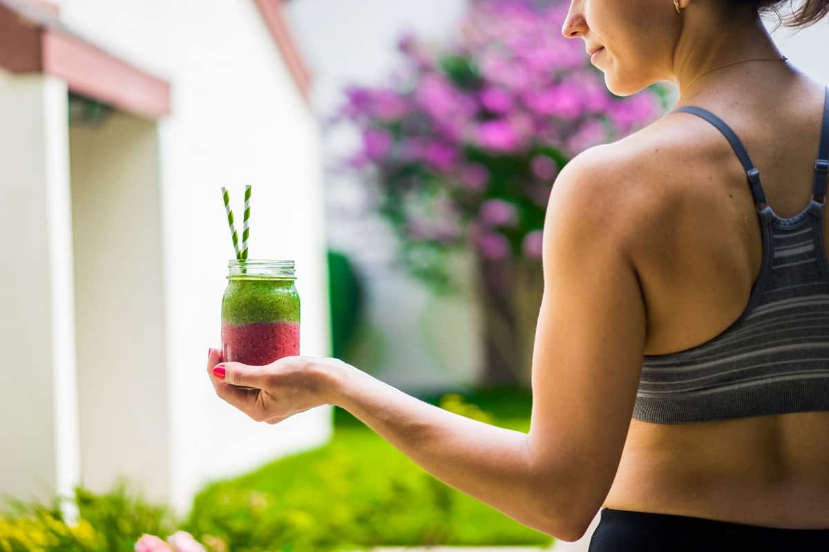 A woman in athletic clothing with a post workout smoothie.