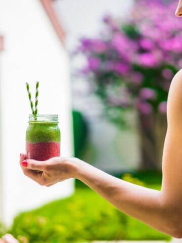 A woman holding a post workout smoothie in her hand.