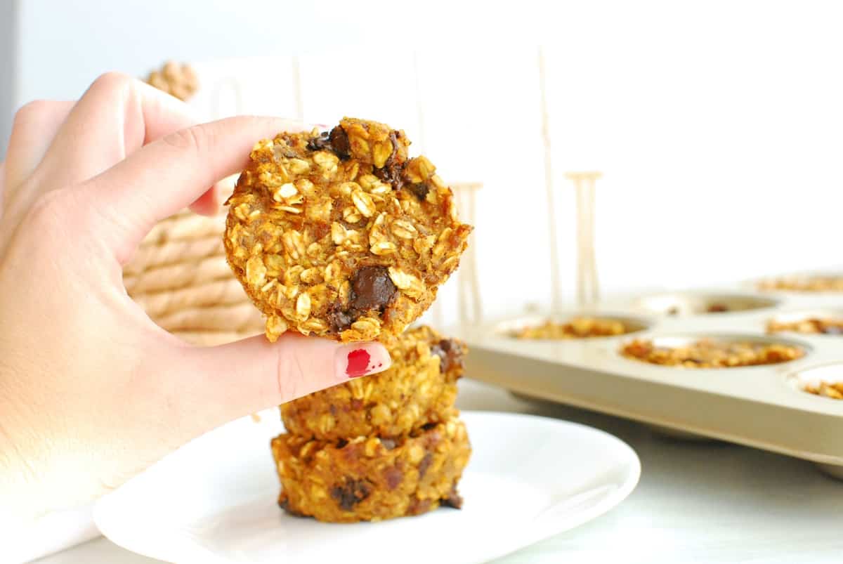 A woman's hand holding a pumpkin baked oatmeal cup.