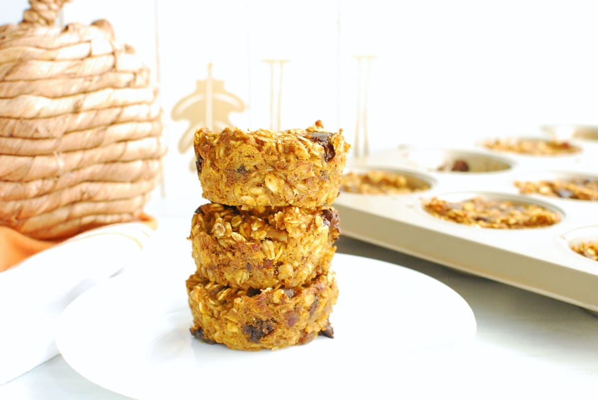 Three pumpkin baked oatmeal cups stacked on top of each other on a white plate.