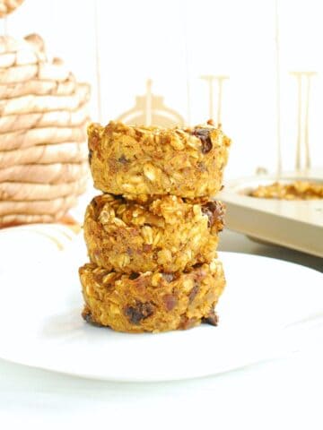 Three pumpkin baked oatmeal cups on a plate, next to a woven pumpkin decoration.