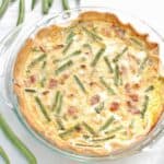 Green bean quiche baked in a glass pie plate.