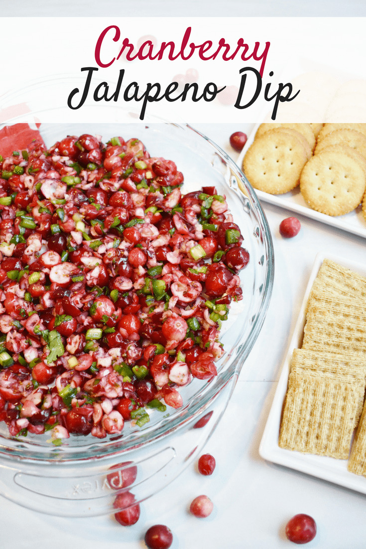 A pie plate full of cranberry jalapeno dip next to crackers.