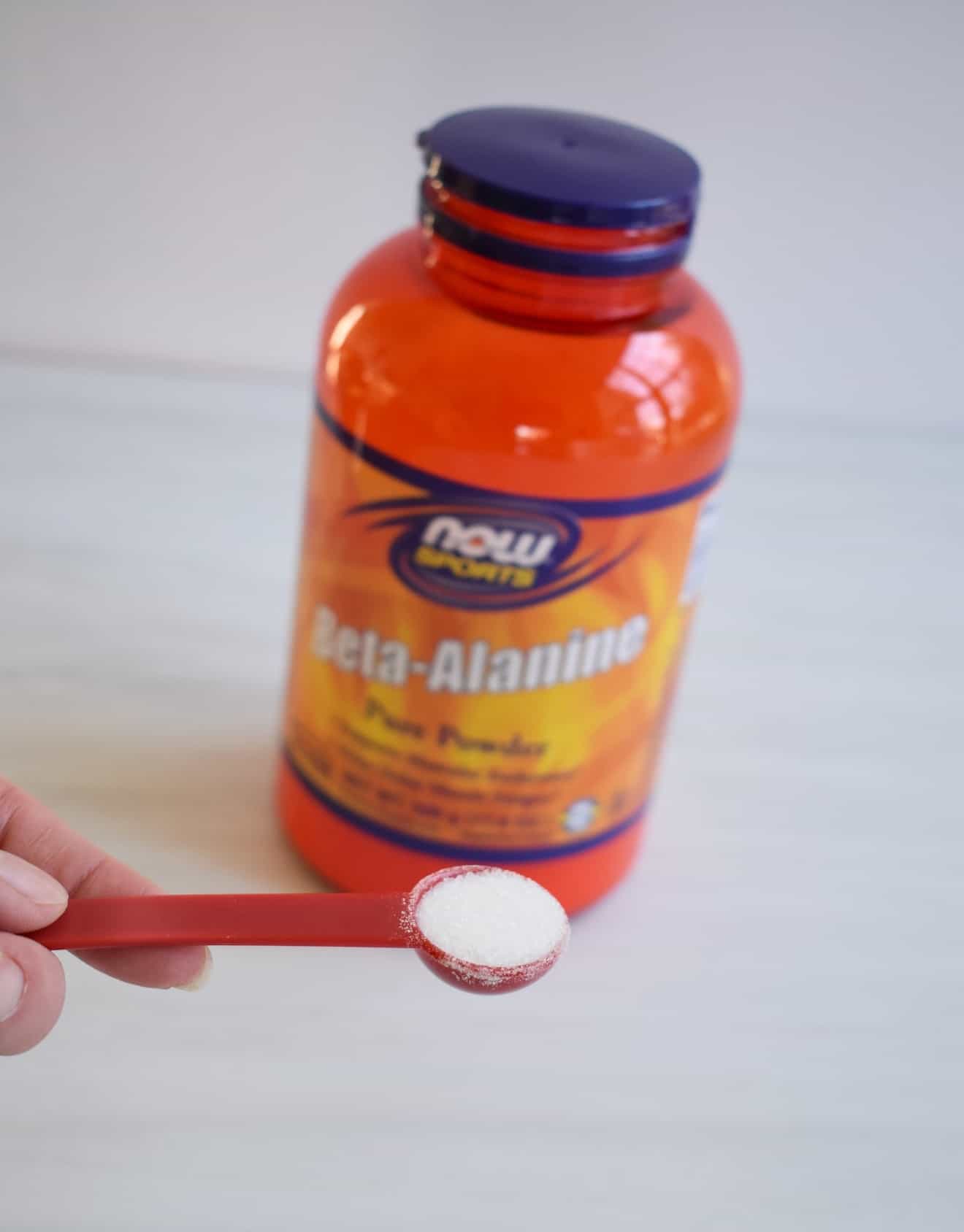 A triathlete measuring out a scoop of beta alanine powder