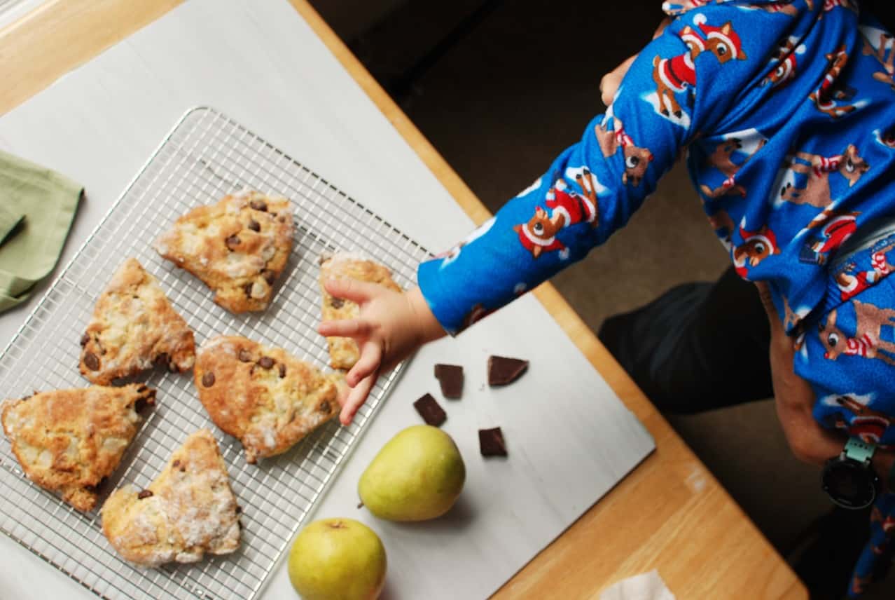 child reaching for a pear and chocolate scone