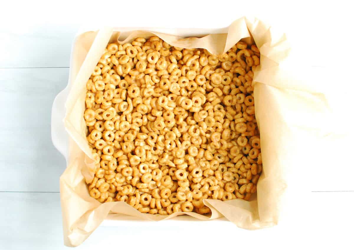 The cereal bar mixture pressed down into a parchment-lined 8x8 dish.