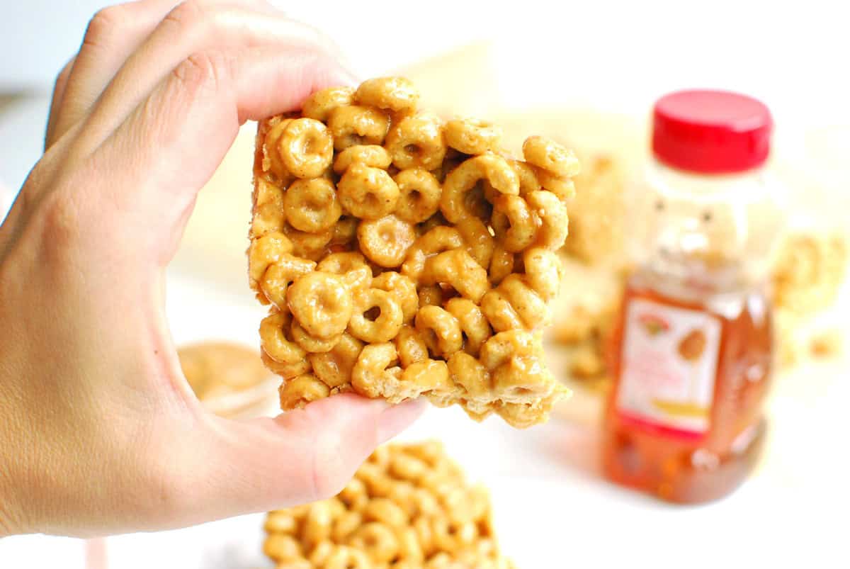 A woman's hand holding a peanut butter honey cheerio bar.