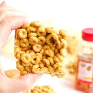 A woman's hand holding a peanut butter honey cheerio bar.