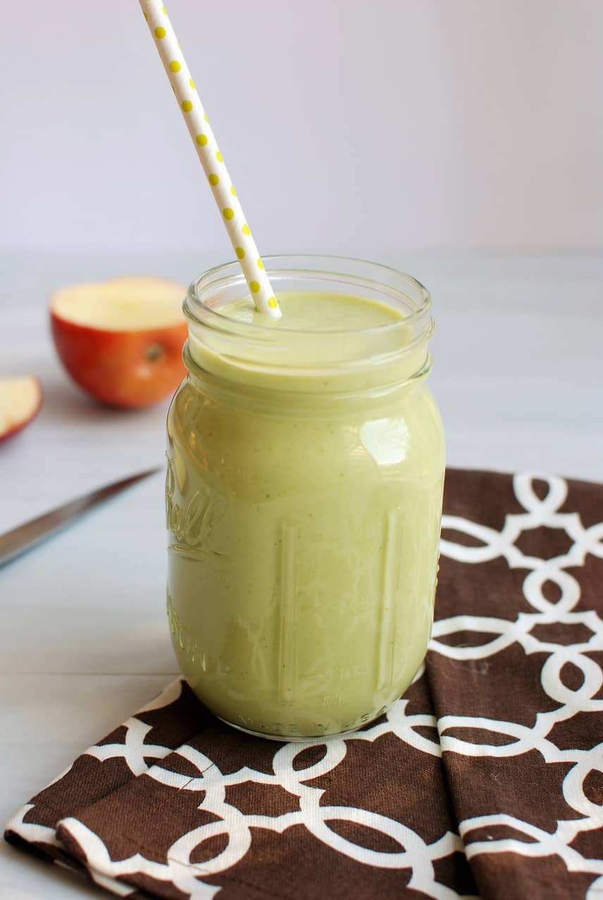 Mason jar full of an arugula apple smoothie on top of a brown napkin
