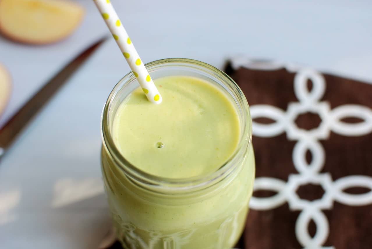 The top of an arugula apple green smoothie in a mason jar with a straw