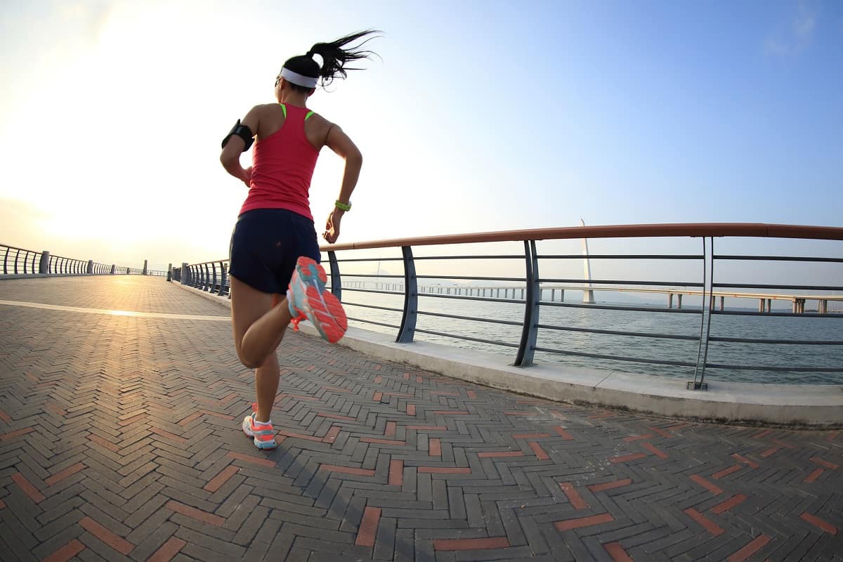 A woman sprinting along a seaside path.