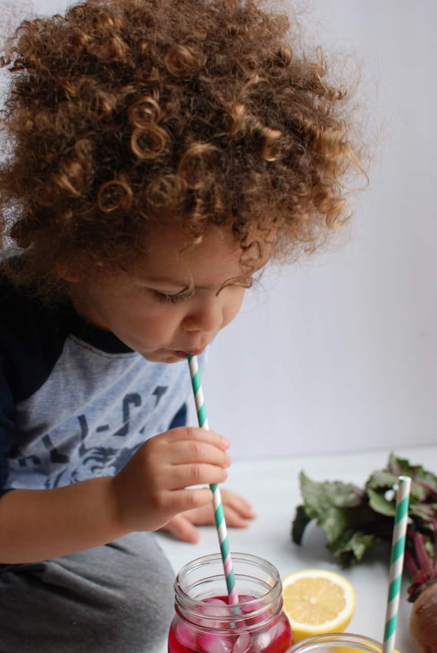 Child drinking beet lemonade from a straw