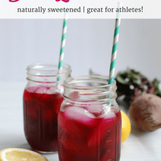 Two mason jars filled with beet lemonade next to a lemon and beet