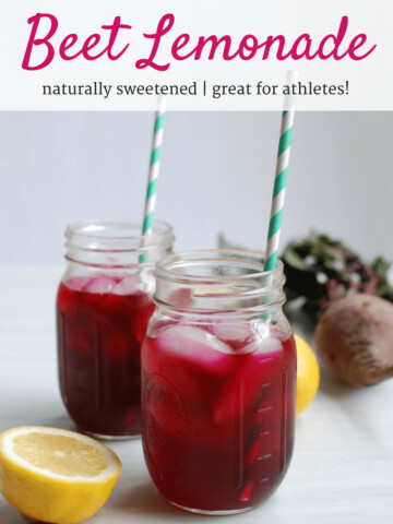Two mason jars filled with beet lemonade next to a lemon and beet