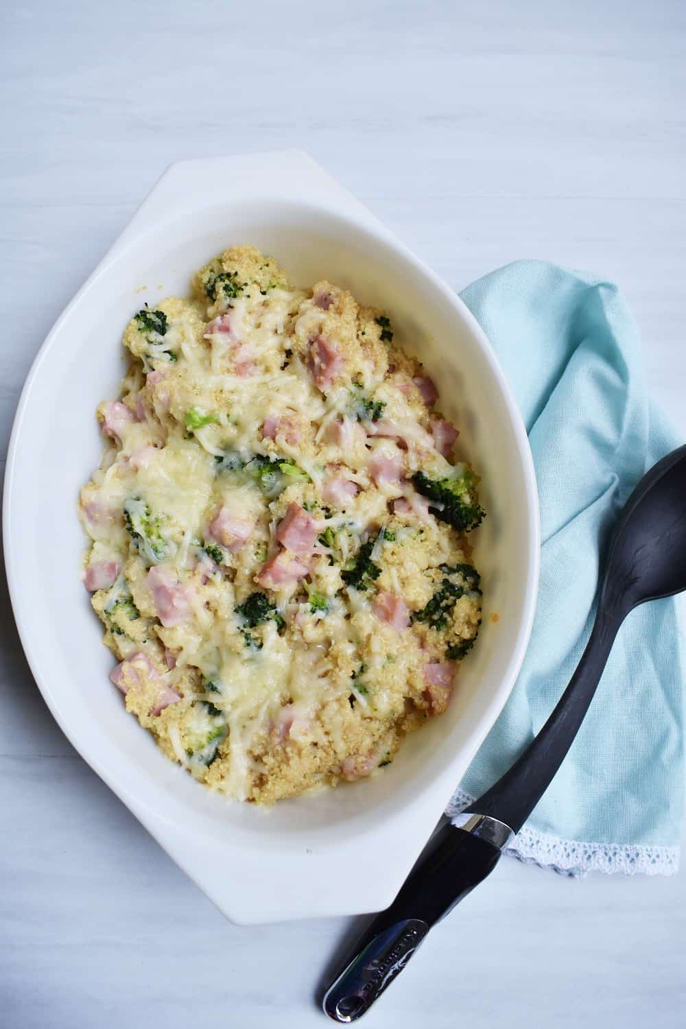 Leftover ham casserole in a white dish next to a black spoon