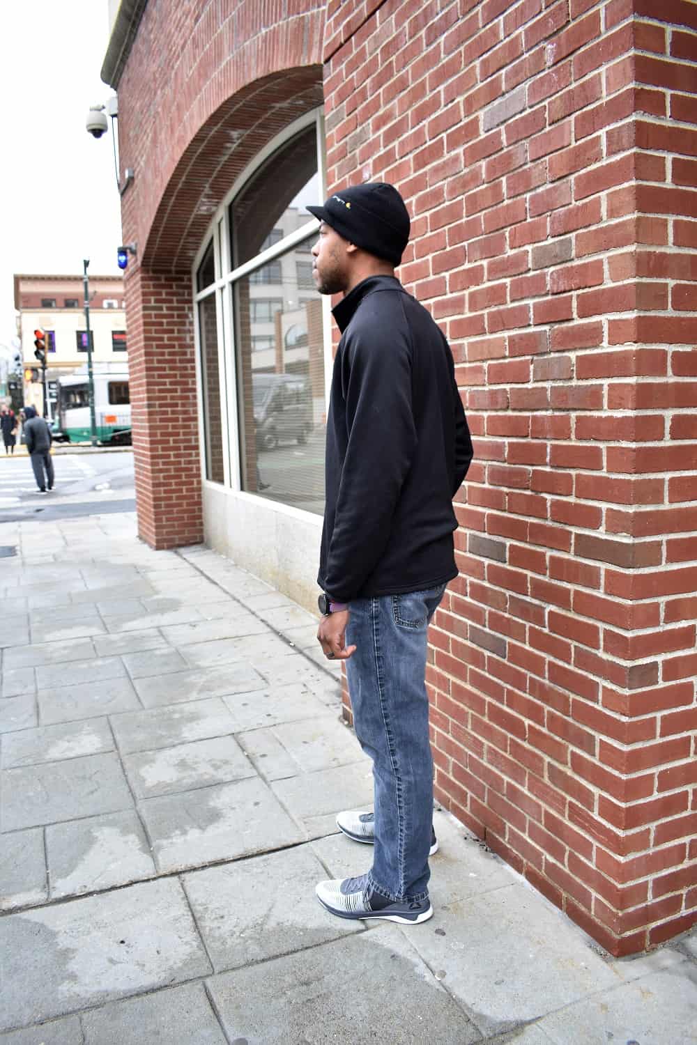 Man wearing black shirt, jeans, and sneakers in the city