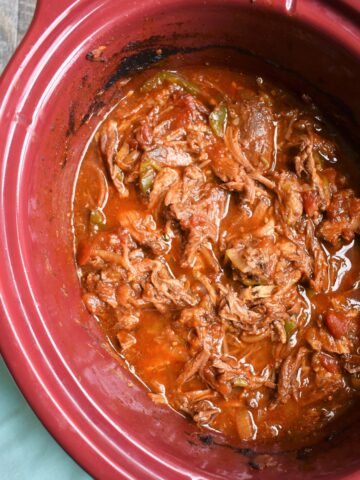 A slow cooker full of shredded beef.
