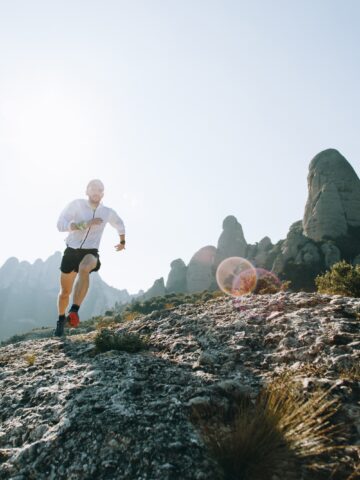 A man running on a sunny day on a mountain.