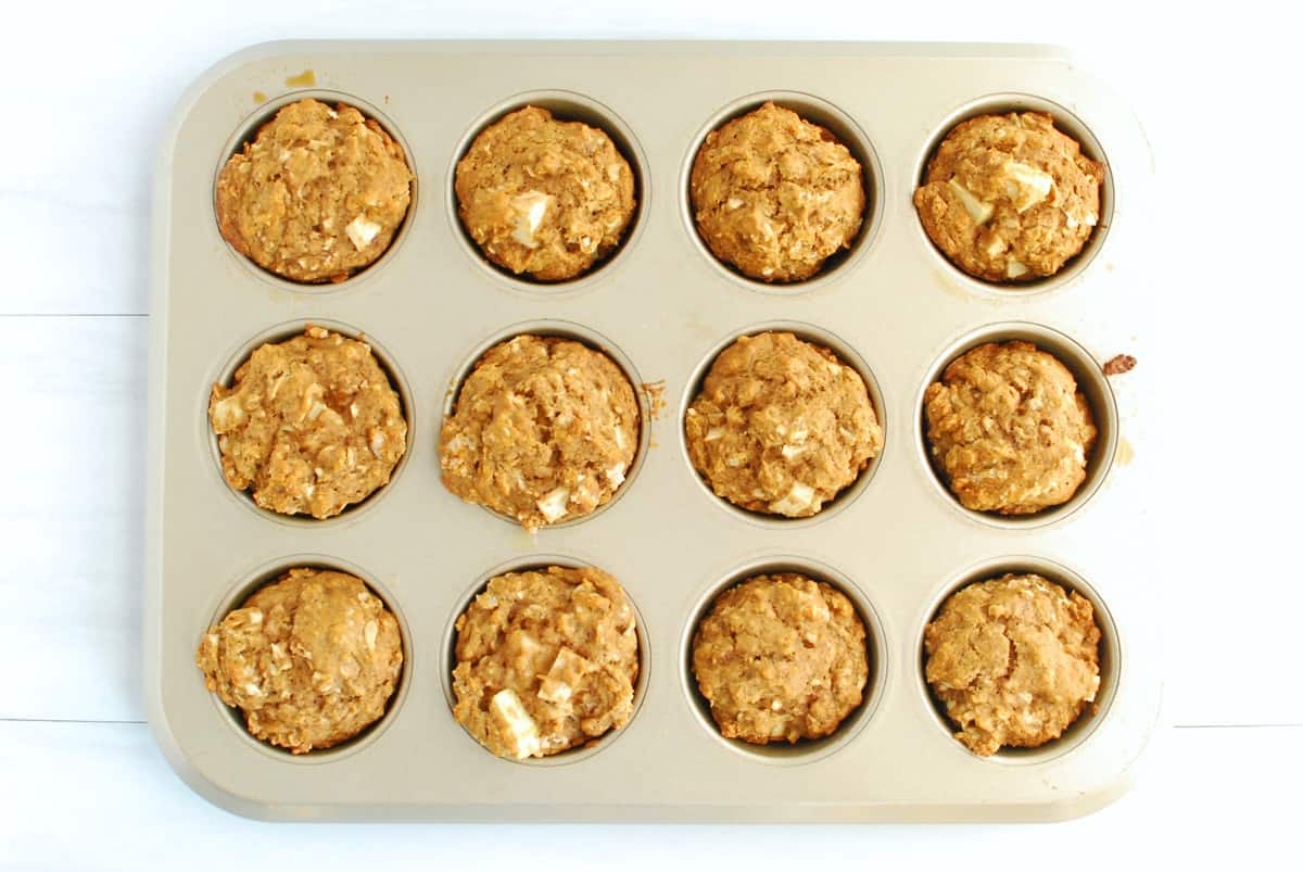 A muffin tin with just-baked vegan apple muffins.