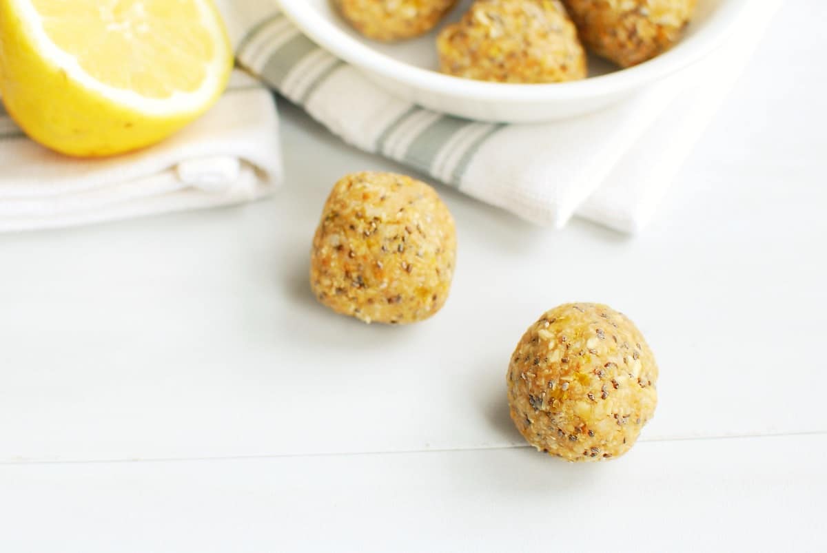 A close up of two lemon energy bites on a white table.